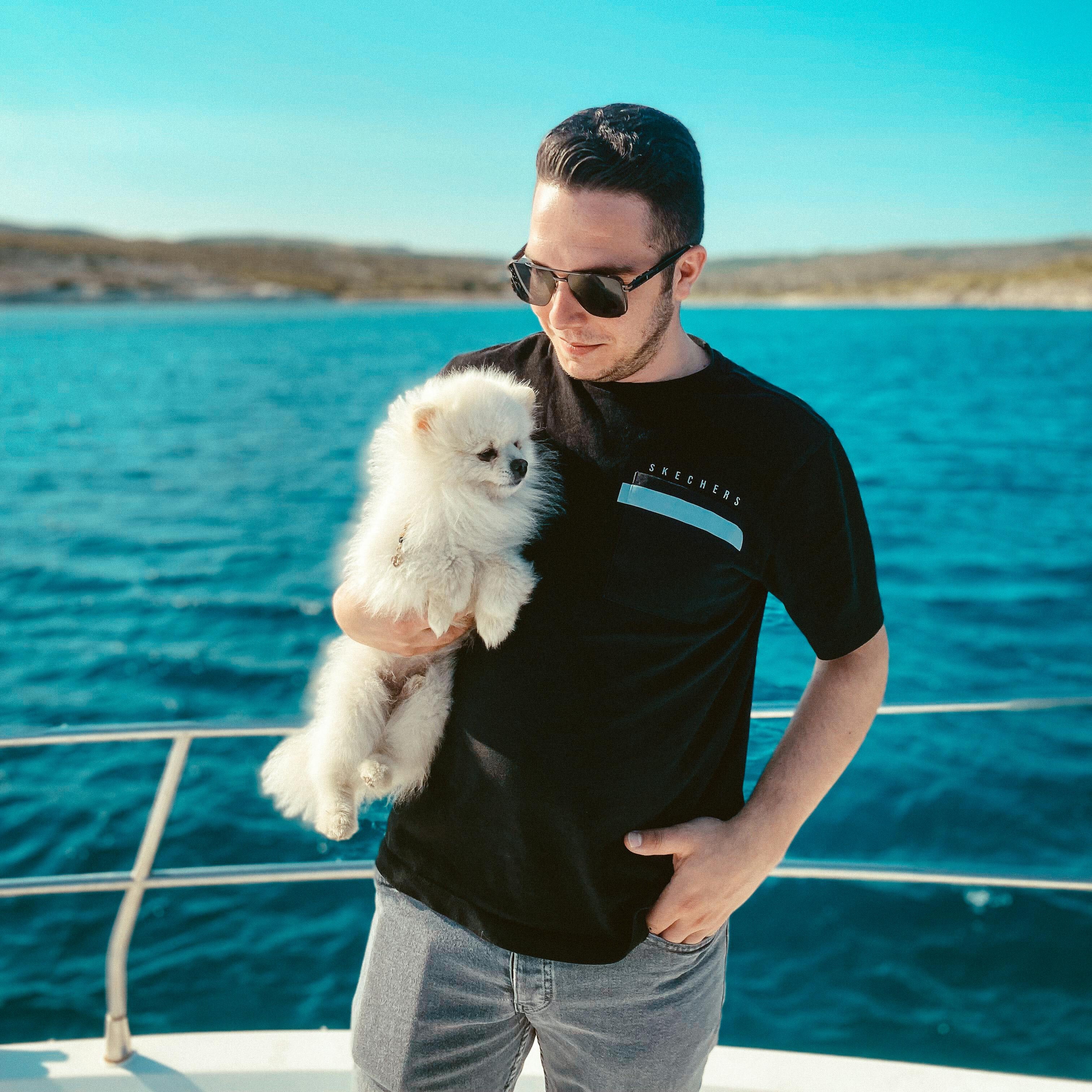 man holding small dog on a boat