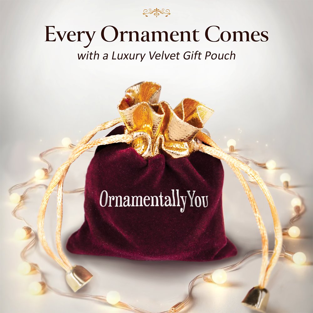 Red velvet gift pouch with gold bow and 'OrnamentallyYou' branding, surrounded by fairy lights on a light gray background.