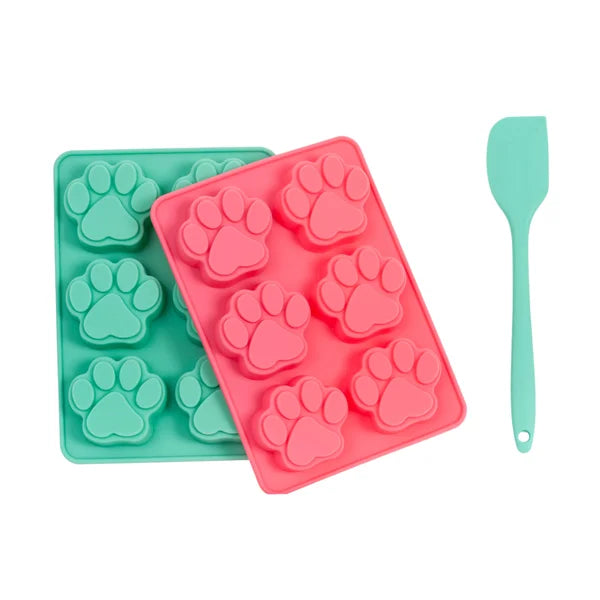 Two silicone molds with paw prints and a green spatula on a white background