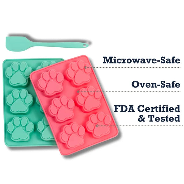 Two silicone paw print molds, one green and one pink, with a spatula on a white background.
