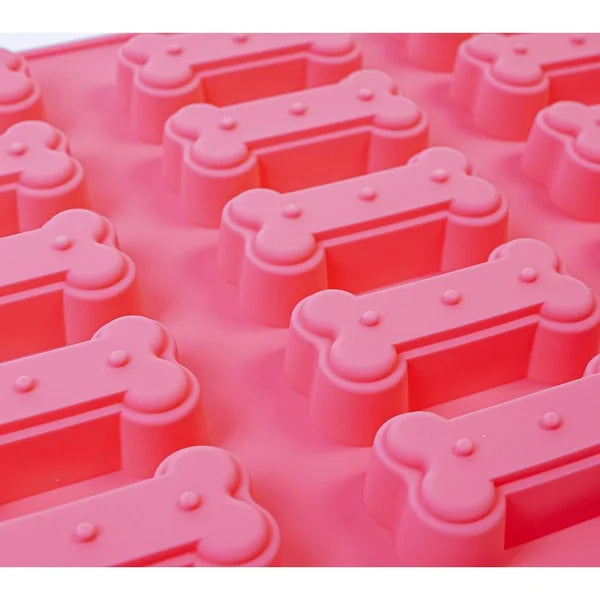 Pink silicone mold with bone-shaped cavities on a white background
