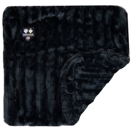 Black quilted blanket with a brand label on a white background