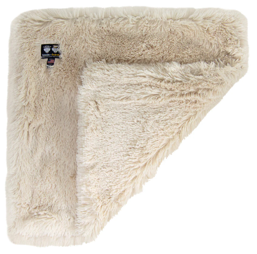 Beige fluffy blanket with a brand label on a white background