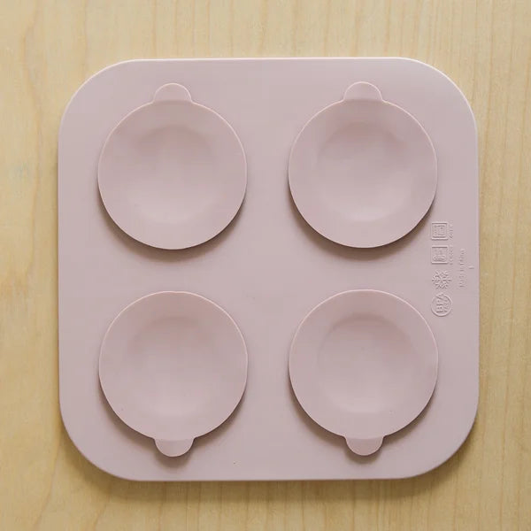 Pink silicone mold with four round cavities on a wooden surface