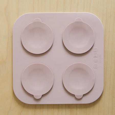 Pink silicone mold with four round cavities on a wooden surface