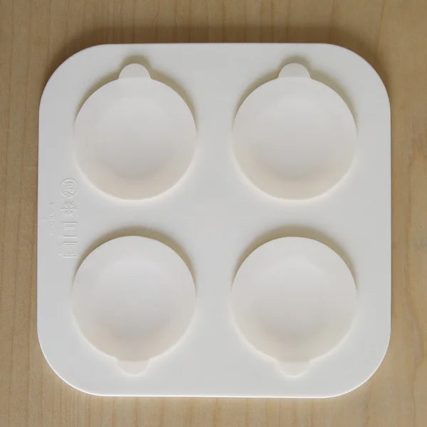 Silicone mold with four round cavities on a wooden surface