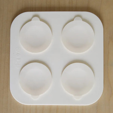 Silicone mold with four round cavities on a wooden surface