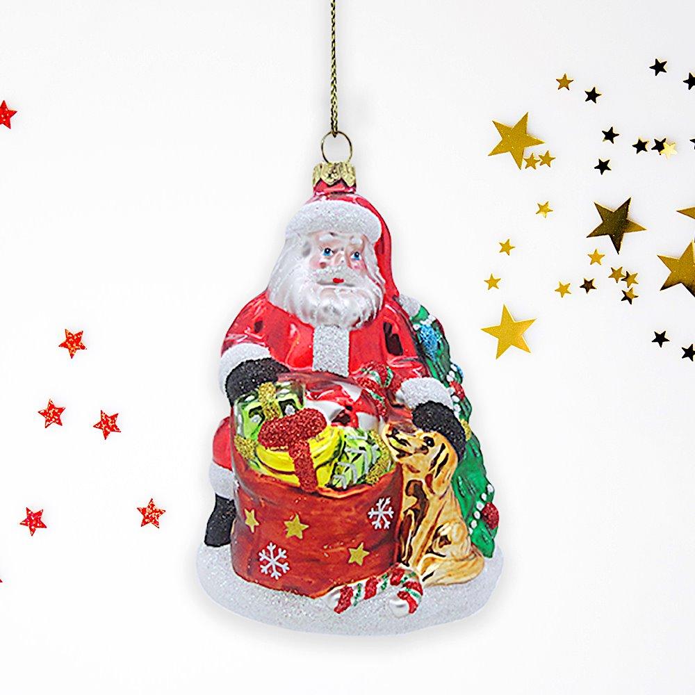 Decorative Christmas ornament of Santa Claus with a sack of toys, surrounded by decorative stars on a white background.