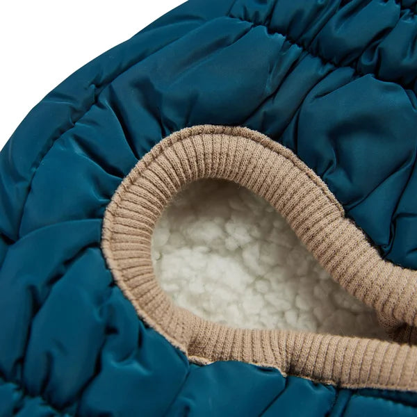 Close-up of a blue puffer jacket with beige interior lining on a white background