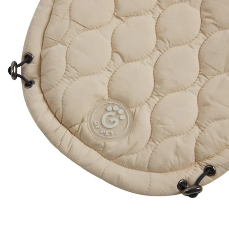 Beige quilted round cushion with a brand logo on a white background