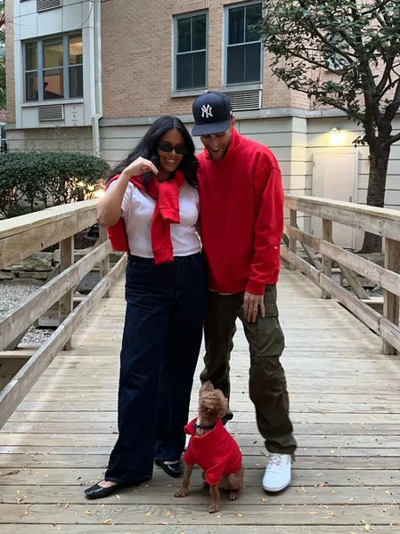Two people and a dog on a wooden deck in front of a building