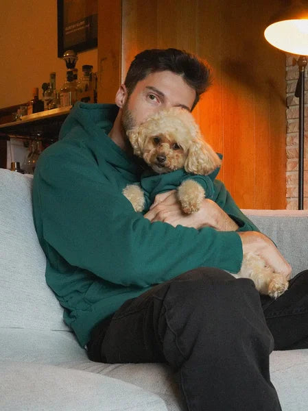 Man holding a small dog on a couch in a cozy living room.
