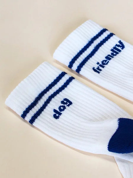 Two white socks with blue stripes and text on a beige background