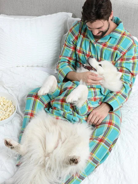 Man in a colorful onesie with two white dogs on a bed
