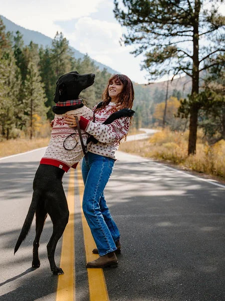 Woman and dog on a road with mountains in the background