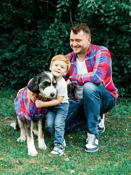 Man and child with a dog sitting on grass