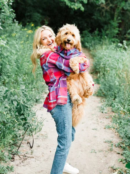 Woman holding a fluffy dog on a path surrounded by greenery