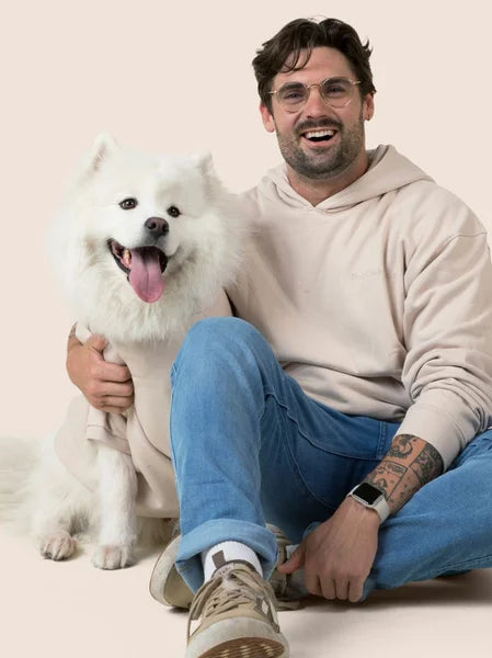 Man sitting with a white dog on a plain background