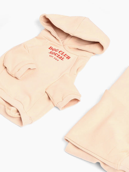 Folded peach hoodie with 'Dog Club Social' text on a white background