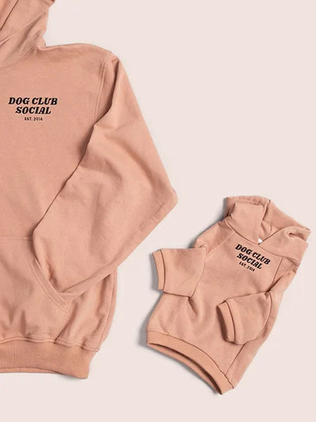 Pink hoodie with 'Dog Club Social' text on a light pink background