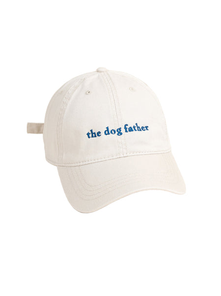 White cap with 'the dog father' text on a beige background