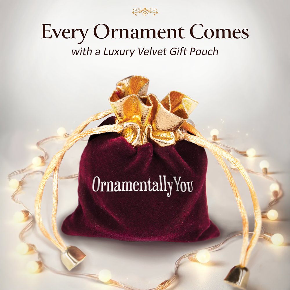 Red velvet gift pouch with gold bow and 'Ornamentally You' branding, surrounded by fairy lights on a light gray background.