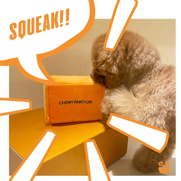 Dog playing with an orange toy labeled 'Chewy Pawton' on a beige background.