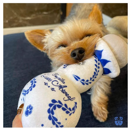 Small dog holding a plush toy with blue and white design