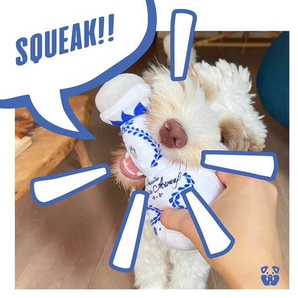 Dog playing with a toy labeled 'SQUEAK!!' on a wooden floor.