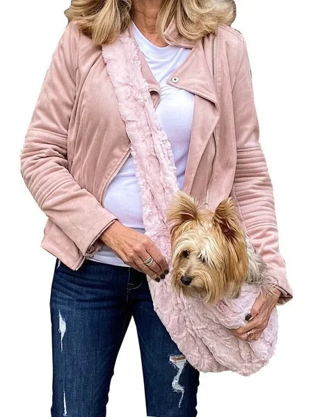 Woman holding a small dog wrapped in a pink blanket against a white background