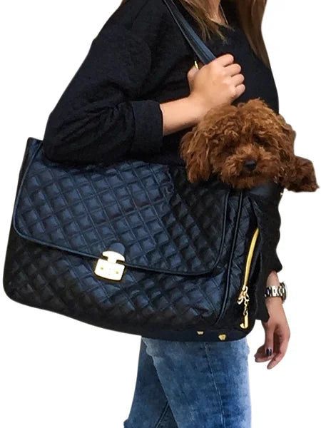 Person holding a navy quilted handbag with a small brown dog peeking out.