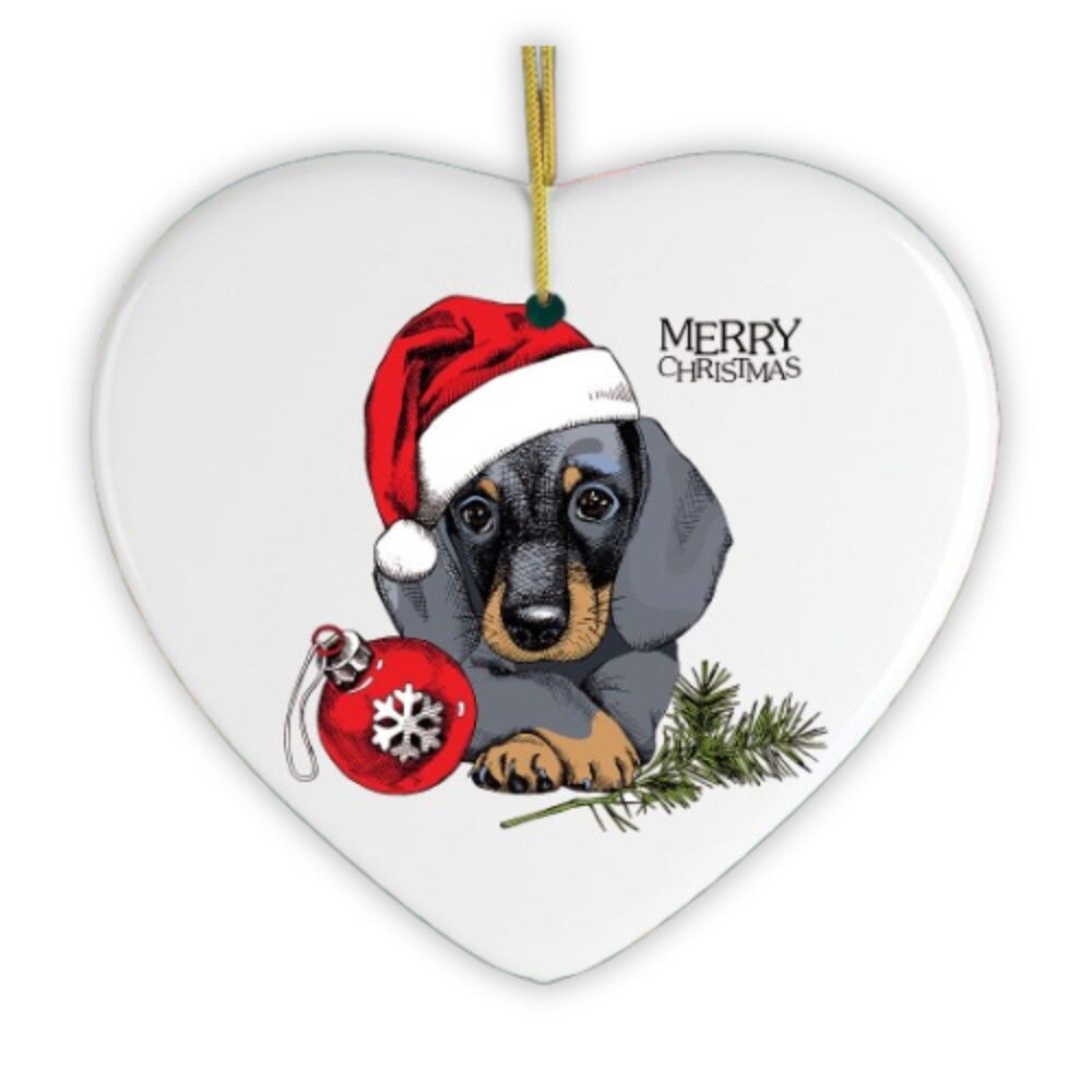 Heart-shaped Christmas ornament with a dachshund wearing a Santa hat and holding a red ornament.