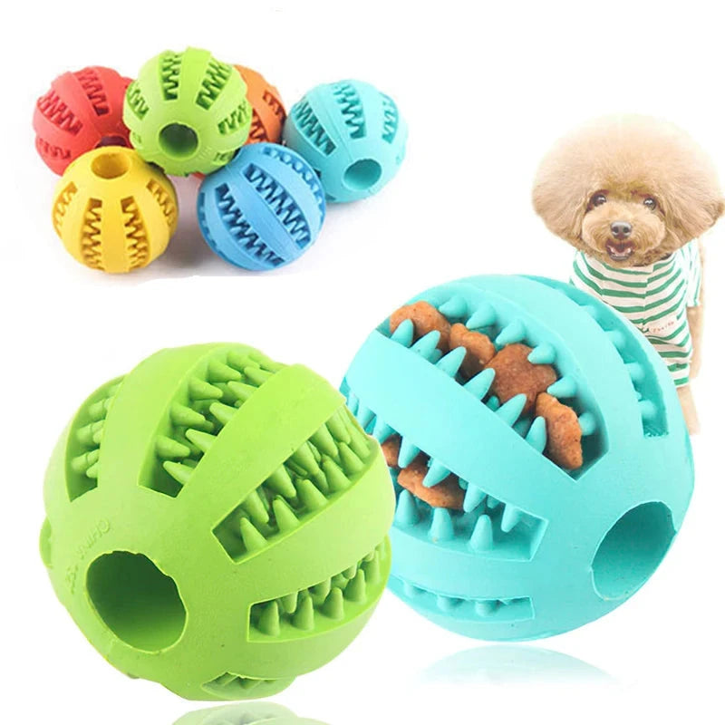 A collection of colorful rubber pet balls designed with grooves for holding treats, promoting dental health. The balls come in blue, green, red, orange, and yellow. A fluffy dog in a green and white striped shirt is shown in the background. One blue Interactive Elasticity Dog Ball Toy - Small Dog Chew & Tooth Cleaning Rubber Food Ball is filled with treats within the grooves.